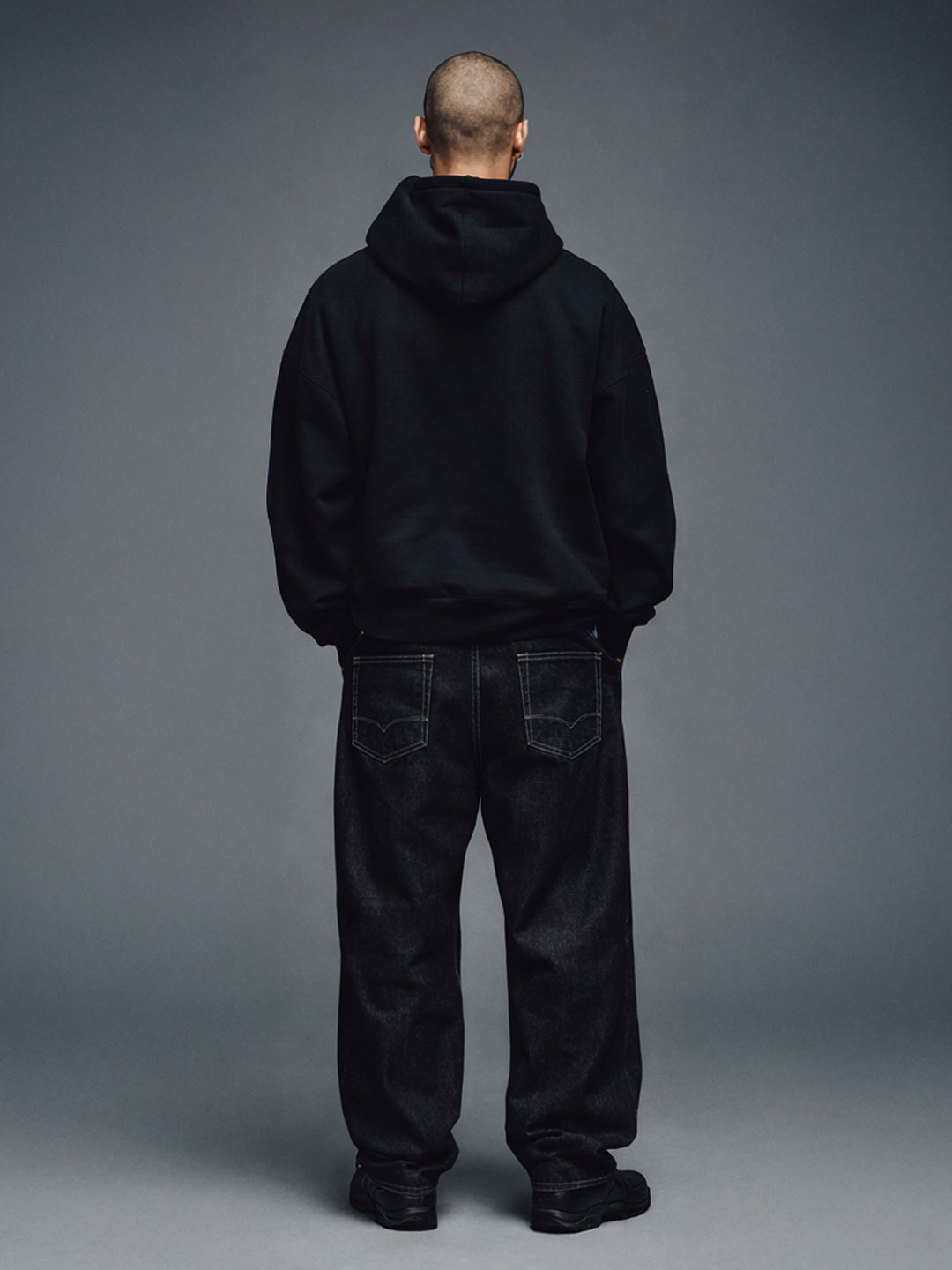 Male model wearing the Champions Hoodie in black, back view with hood down