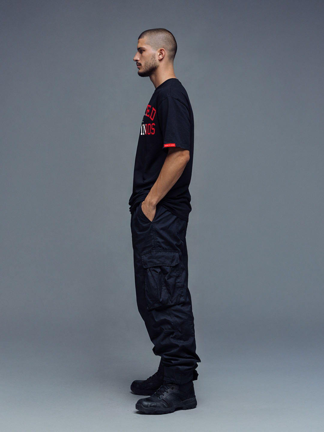Male model wearing the Firmes y Unidos black t-shirt, side view with red sleeve tab
