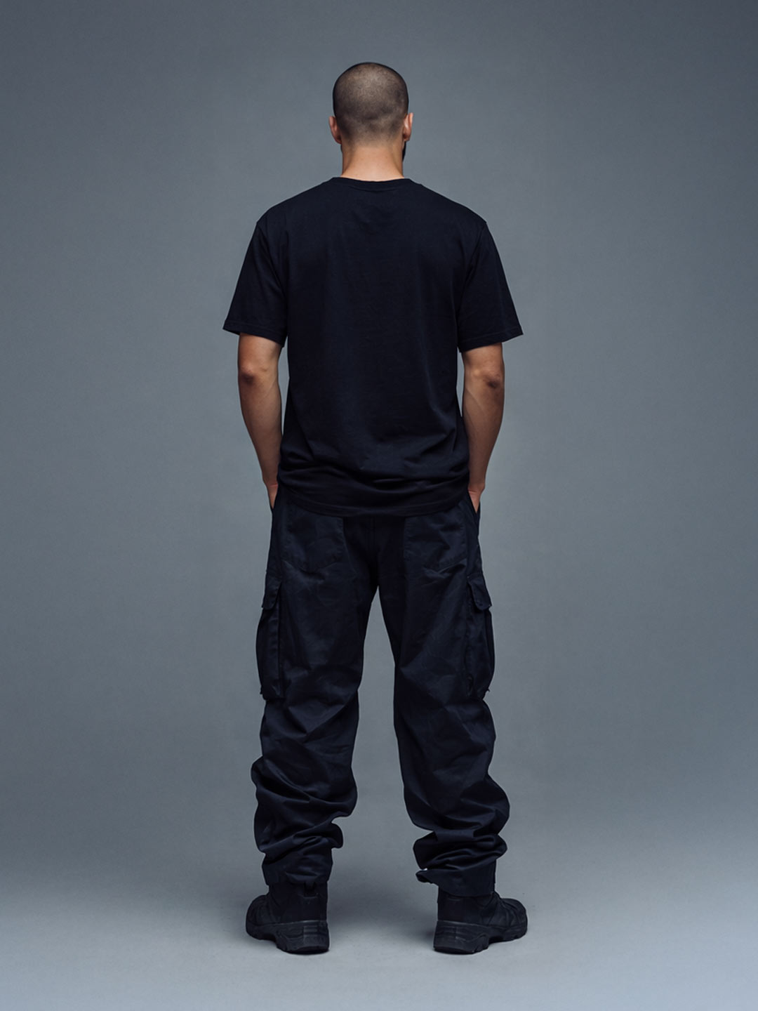 Male model wearing the Firmes y Unidos black t-shirt, back view