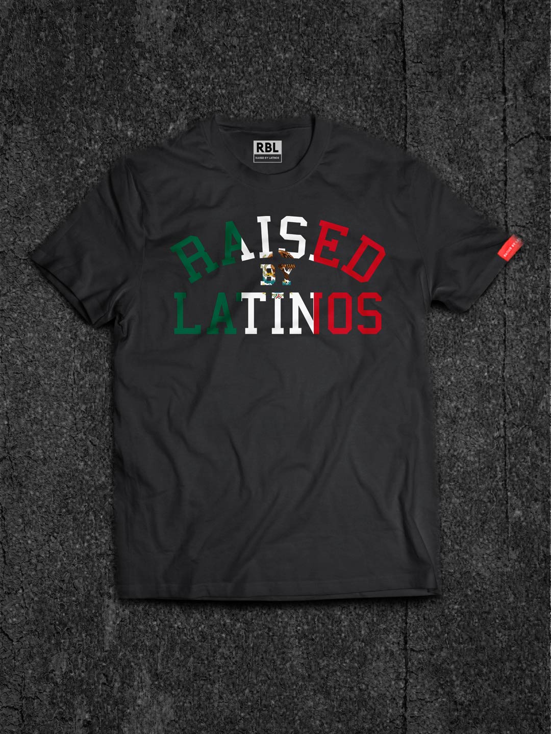 Firmes y Unidos black t-shirt, flat lay on asphalt with green, white and red RAISED BY LATINOS chest print